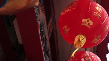 Slow motion of the Chinese red lantern lights then vibrating by the wind Chinese new year decoration, with blessing text mean happy, healthy, and wealthy, at Chinese temple roof