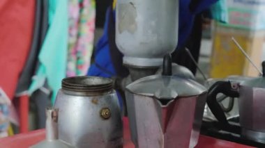 A street vendor is preparing tea, pouring hot water from termos and close it, a bit old and authentic kettles and teapot in the shoot. High quality 4k footage