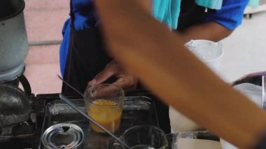 A process of making Thai milk tea or Indian masala cha, street vendor mixing the tea brown color, close up shot brown hands and black glove. High quality 4k footage