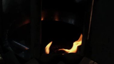 A fire flame burns in an oil pot. metal construction around, or steel box some beautiful orange reflections in slow motion. High quality FullHD footage, Recorded by Fujifilm XT4