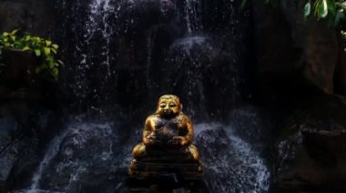 Şişko Altın Buda heykeli, ağır çekimde yüzen suyla çevrilidir. Huzur ve sükunet getirir. Yüksek kaliteli FullHD görüntüler.