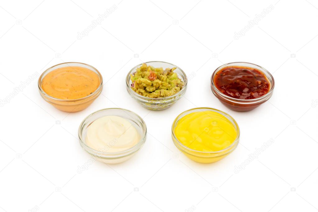 Bowls with Mexican cuisine sauces, guacamole, chili, cheese, paprika on a white plate.