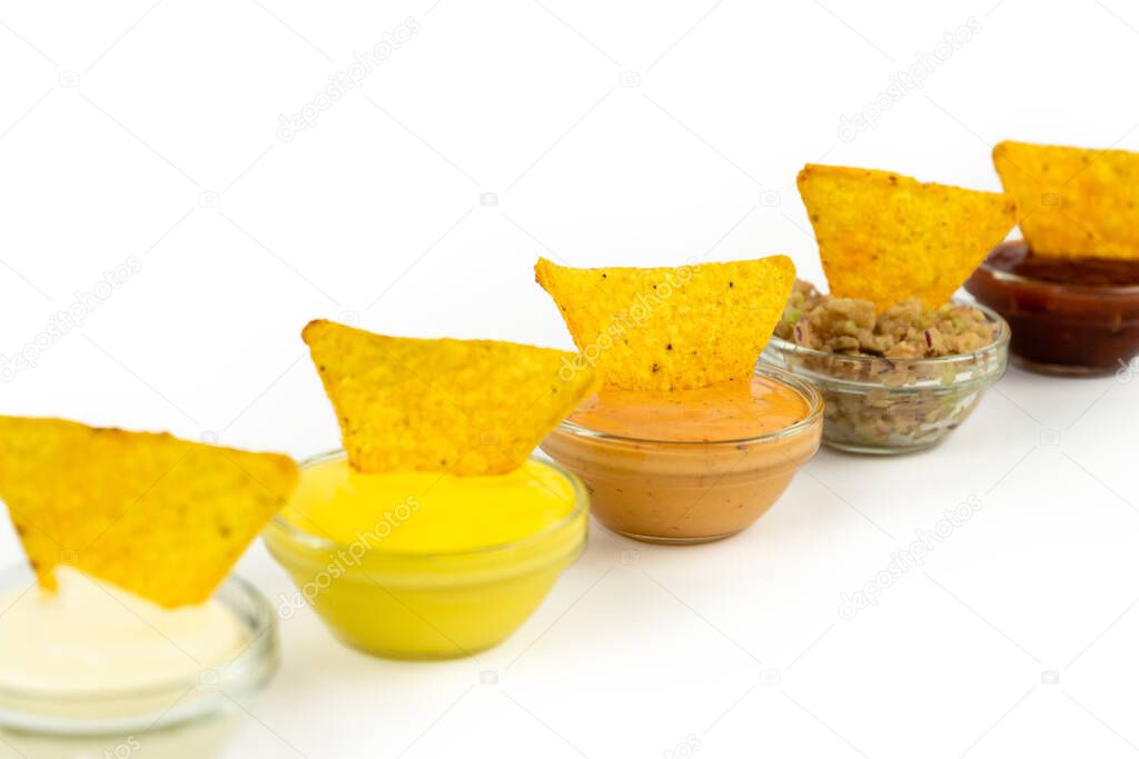 Bowl with sauce on a white plate with nachos corn chips. Isolation on a white background.