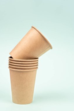 Renkli bir arkaplanda içmek için sıraya dizilmiş tek kullanımlık kağıt bardaklar. Dikey fotoğraf