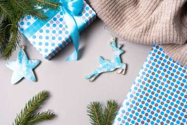 Epoksi reçineden yapılmış, gri arka planda hediyeler ve ladin dallarıyla süslenmiş bir Noel ağacının mavi Noel süslemeleri. Üst görünüm