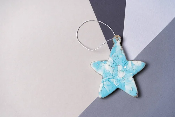 Blue star made from epoxy resin on a gray background. Christmas decorations on the tree. Copy space