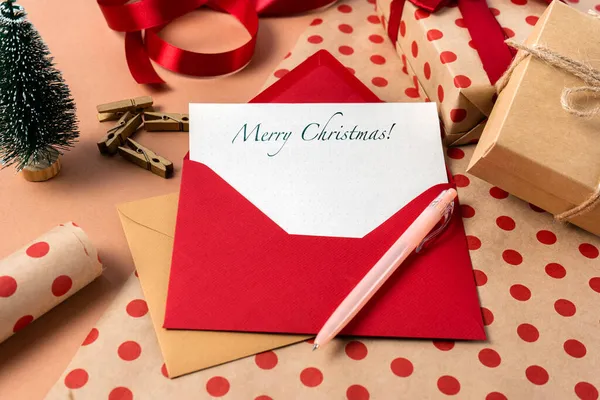 Christmas card with wishes in a red envelope on the background of gift wrapping. Close up