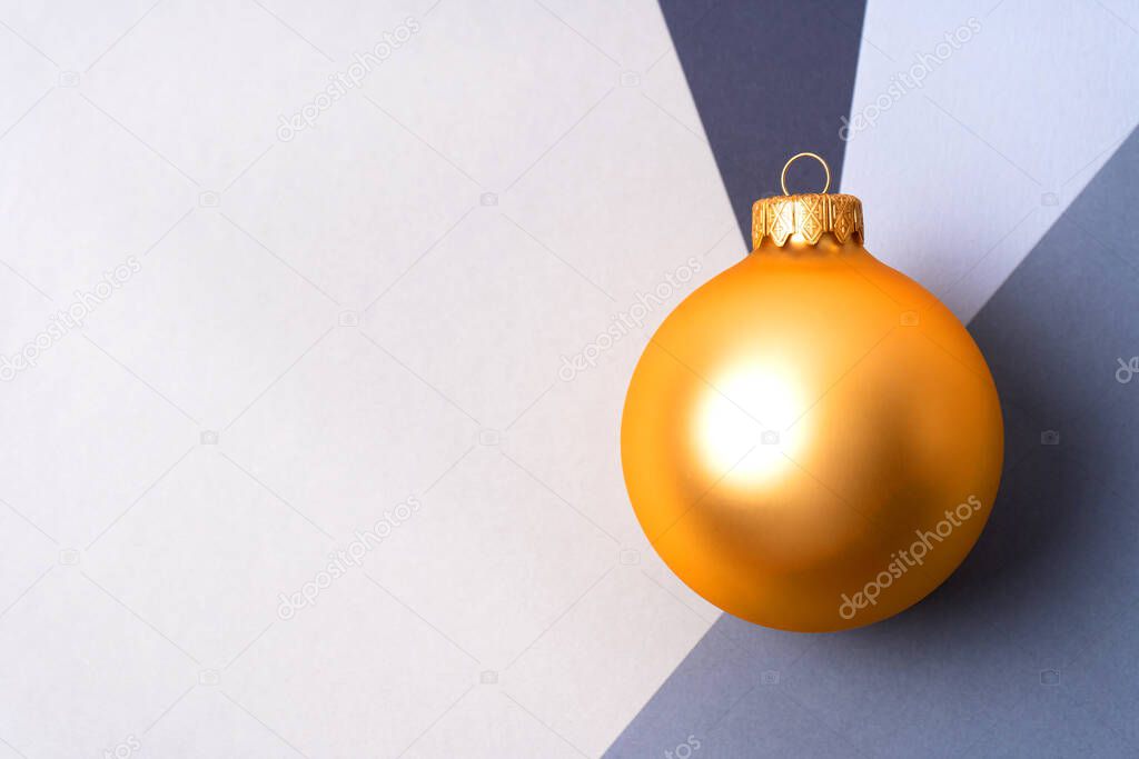 Golden Christmas ball at the intersection of four shades of gray with copy space. Christmas and New Year concept