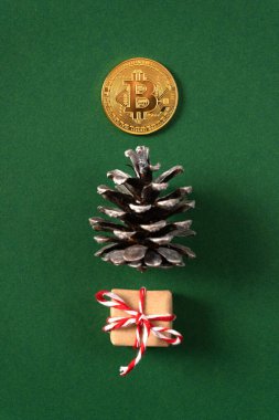 Çam kozalaklarından, hediyelerden ve yeşil arka planda bitcoin parasından yapılmış Noel ağacı konsepti. Dikey fotoğraf. 