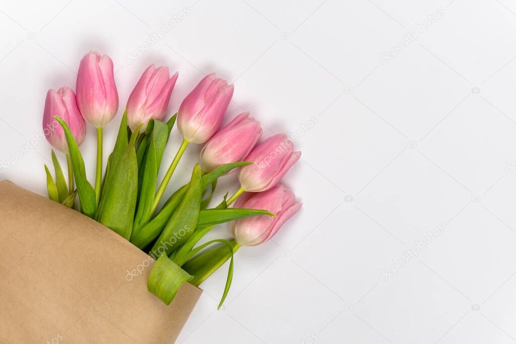Pink tulips in craft paper on white background with copy space or logo. Easter. Valentine's Day. Mother's day. Top view