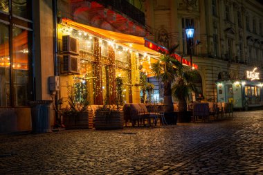 Bükreş Eski Şehir Meydanı, açık kafeler, binalar, market tezgahları, kubbe ve kentteki sokak geceleri sokakta yürüyen insanlar, Bükreş 'teki kafe, eski kasaba, turuncu ışık