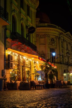 Bükreş Eski Şehir Meydanı, açık kafeler, binalar, market tezgahları, kubbe ve kentteki sokak geceleri sokakta yürüyen insanlar, Bükreş 'teki kafe, eski kasaba, turuncu ışık