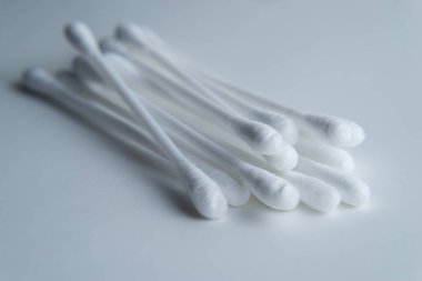 Gri arkaplanda beyaz pamuklu çubuk ya da pamuk tomurcukları var. Kulaklar için beyaz plastik bir tabanda, 