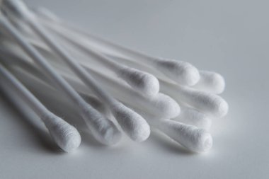 Gri arkaplanda beyaz pamuklu çubuk ya da pamuk tomurcukları var. Kulaklar için beyaz plastik bir tabanda, 