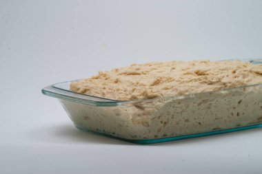 Homemade bread dough in the glass cooking container isolated on the white background,  Cooking Wheat Sourdough clipart
