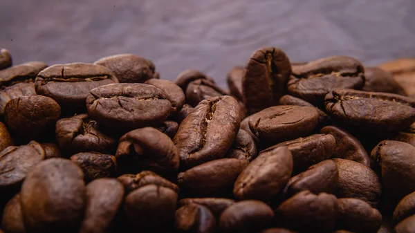 Kahve çekirdeği. Kahve çekirdekleri yüzeyde yayılır. Kavrulmuş kahve çekirdeği arka planı, desen