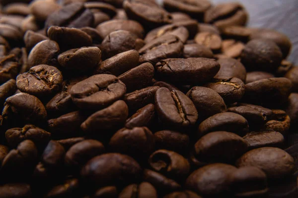 Kahve çekirdeği. Kahve çekirdekleri yüzeyde yayılır. Kavrulmuş kahve çekirdeği arka planı, desen