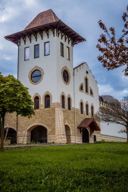 Purcari, Moldova 27.04.2022. Çağdaş şarap imalathanesi Purcari, Moldova 'nın Purcari köyünde, yağmurlu bir bahar gününde, yeşillik, ahşap köprü, göl, logo, beyaz kuğu, belvedere, üzüm bağı,