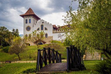Purcari, Moldova 27.04.2022. Çağdaş şarap imalathanesi Purcari, Moldova 'nın Purcari köyünde, yağmurlu bir bahar gününde, yeşillik, ahşap köprü, göl, logo, beyaz kuğu, belvedere, üzüm bağı,