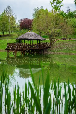 Purcari, Moldova 27.04.2022 pavyon, yazlık odun, yeşillik, ahşap köprü, göl, logo, beyaz kuğu, belvedere, üzüm bağı, çardak, rahat bir yer. Göl kıyısındaki ahşap ağaç ve iskele.