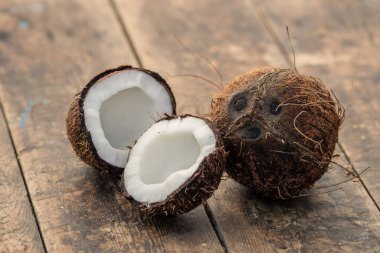 Olgun bir delik ve eski ahşap bir arka planda yarım hindistan cevizi. Hindistan cevizi kreması ve yağ..