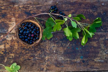 Ahşap bir arka planda izole edilmiş bir kasede kara frenk üzümü. Frenk üzümü. Üst görünüm