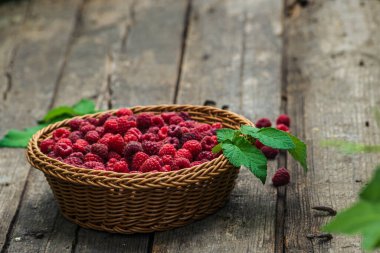 Taze organik olgun ahududu ahşap masa örülmüş sepet meyvesi,
