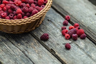 Taze organik olgun ahududu ahşap masa örülmüş sepet meyvesi,