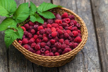 Taze organik olgun ahududu ahşap masa örülmüş sepet meyvesi,