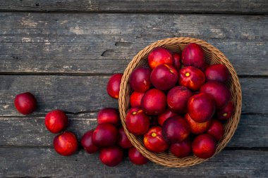 Bir tepsi taze kırmızı nektarin. Ahşap arka plan. Üst manzara taze organik ahşap masa arka plan örülmüş sepet sulu meyve