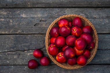 Bir tepsi taze kırmızı nektarin. Ahşap arka plan. Üst manzara taze organik ahşap masa arka plan örülmüş sepet sulu meyve