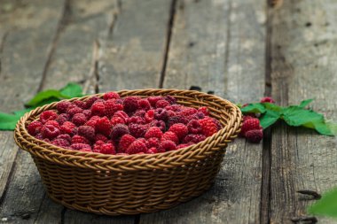 Taze organik olgun ahududu ahşap masa örülmüş sepet meyvesi,