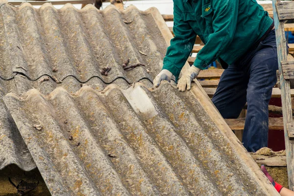 Risks nonProfessionals unprotected remove sheets of asbestos material from the roof of a rural home House with old, danger