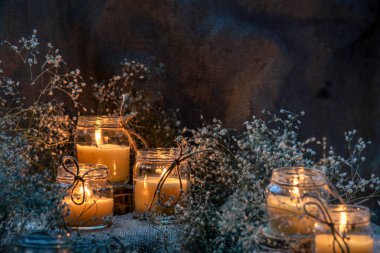 Wax handmade home-based  Burning white candle in the jar coarse textile Vintage  glow Flame dry bouquet gypsophila flower rustic dark mood orange blue light