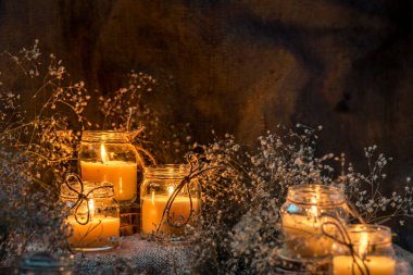 Wax handmade home-based  Burning white candle in the jar coarse textile Vintage  glow Flame dry bouquet gypsophila flower rustic dark mood orange blue light