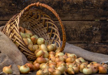 Tahta masada taze kırmızı soğan, üst görünüm, organik gıda kahverengi dilimler, hasır sepetin dışındaki sade ham kesim tahtası Ampul Gıda yerel çiftçi marketini içeriyor