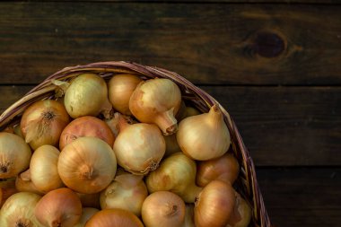 Tahta masada taze kırmızı soğan, üst görünüm, organik gıda kahverengi dilimler, hasır sepetin dışındaki sade ham kesim tahtası Ampul Gıda yerel çiftçi marketini içeriyor
