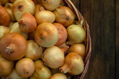 Tahta masada taze kırmızı soğan, üst görünüm, organik gıda kahverengi dilimler, hasır sepetin dışındaki sade ham kesim tahtası Ampul Gıda yerel çiftçi marketini içeriyor