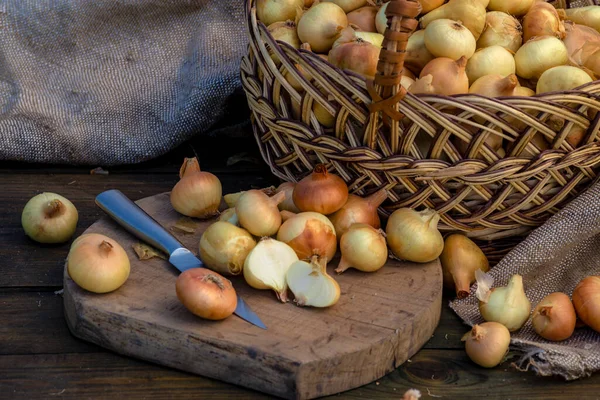 Tahta masada taze kırmızı soğan, üst görünüm, organik gıda kahverengi dilimler, hasır sepetin dışındaki sade ham kesim tahtası Ampul Gıda yerel çiftçi marketini içeriyor