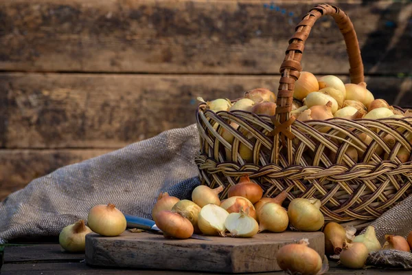 Tahta masada taze kırmızı soğan, üst görünüm, organik gıda kahverengi dilimler, hasır sepetin dışındaki sade ham kesim tahtası Ampul Gıda yerel çiftçi marketini içeriyor