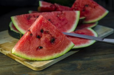Lezzetli karpuz açık hava ahşap masa, yeşil doğal arka plan dilimleme güneşli gün, hurda, taze olgun kırmızı yaprak, yaz güneşli bahçe suyu organik tatlı meyve, vejetaryen yemeği lezzetli dilimlenmiş tahta tabak