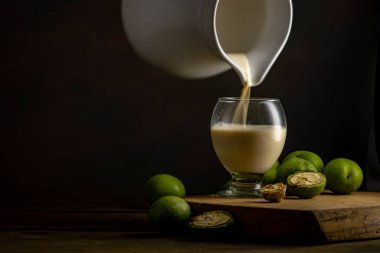 Yeşil ceviz çekirdekleri, ahşap masa yağı fındık olgunlaşmamış kabuklar sağlıklı yiyecek, eski kırsal masa özgeçmişi hasat, organik ev yapımı bitki sütü sütü sütsüz cam bardak.