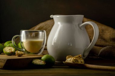 Yeşil ceviz çekirdekleri, ahşap masa yağı fındık olgunlaşmamış kabuklar sağlıklı yiyecek, eski kırsal masa özgeçmişi hasat, organik ev yapımı bitki sütü sütü sütsüz cam bardak.