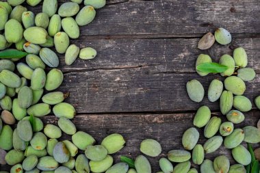 Green almonds background   fresh raw unripe wooden rustic table blurred garden background leaves, Top view concept with copy space shell  tree branch pattern texture