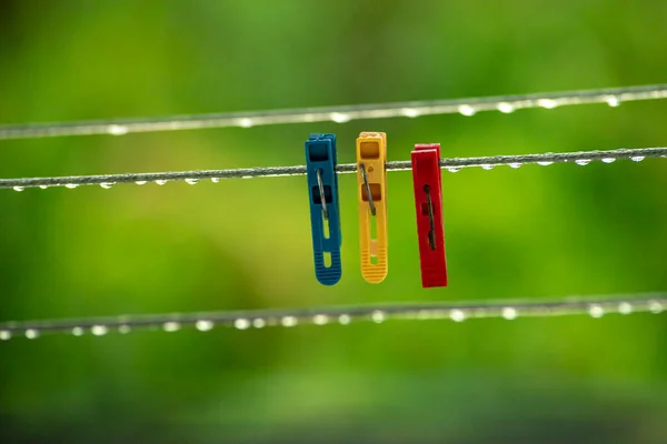 clothing lines of a clothes spin with many raindrops at the string in front of a dark background, after the rain. Retro way of doing the laundry. peg blue yellow reed