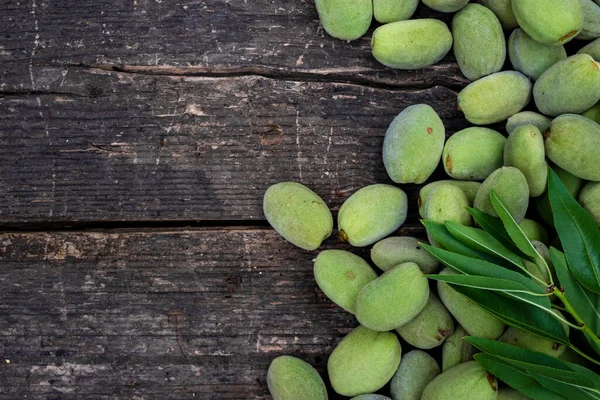 Green almonds background   fresh raw unripe wooden rustic table blurred garden background leaves, Top view concept with copy space shell  tree branch pattern texture