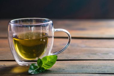 Herbal mint tea cup Transparent glass dark background wooden table still life honey bowl metal kettle teapot spoon cozy