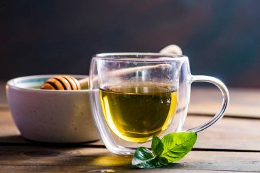 Herbal mint tea cup Transparent glass dark background wooden table still life honey bowl metal kettle teapot spoon cozy