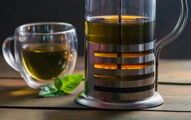 Herbal mint tea cup Transparent glass dark background wooden table still life honey bowl metal kettle teapot spoon cozy