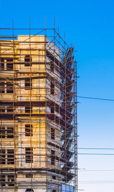 site scaffolding Apartment building under construction on a sunny day Multi-storey residential wooden structure street tlong exposure. car